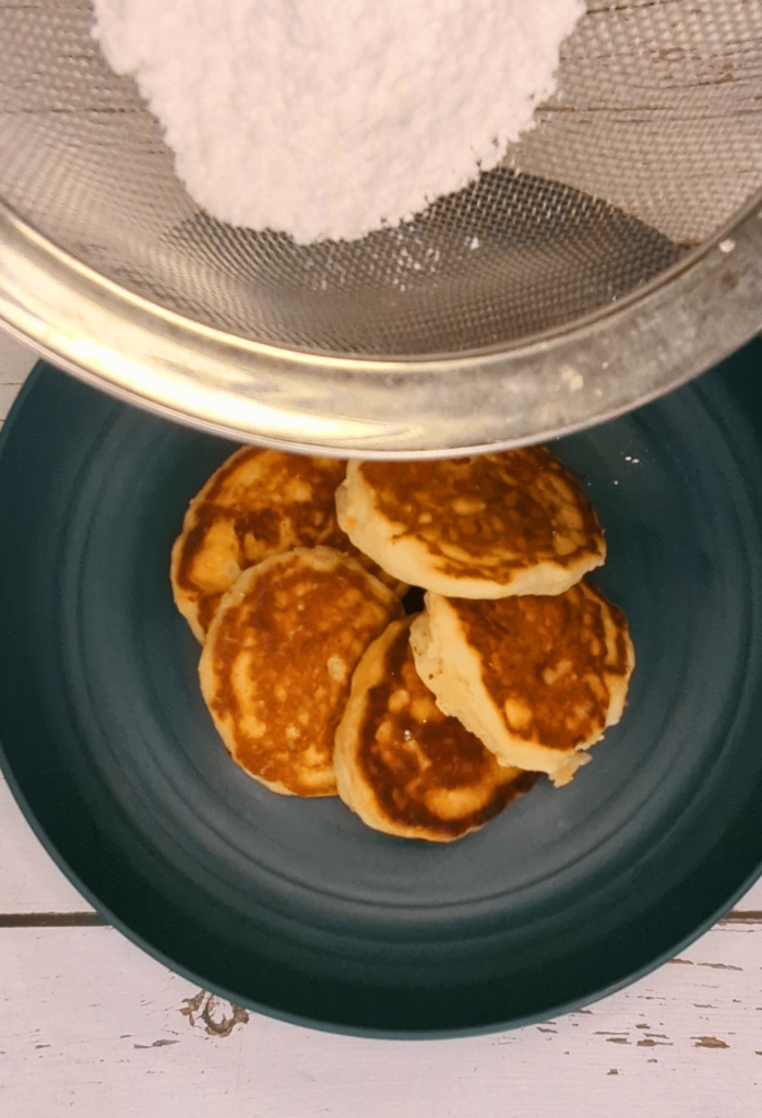 sifting powdered sugar over pancakes